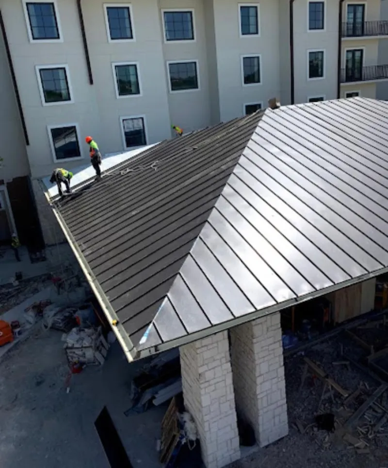 Crew installing standing seam metal roof panels on a commercial project in Mount Juliet